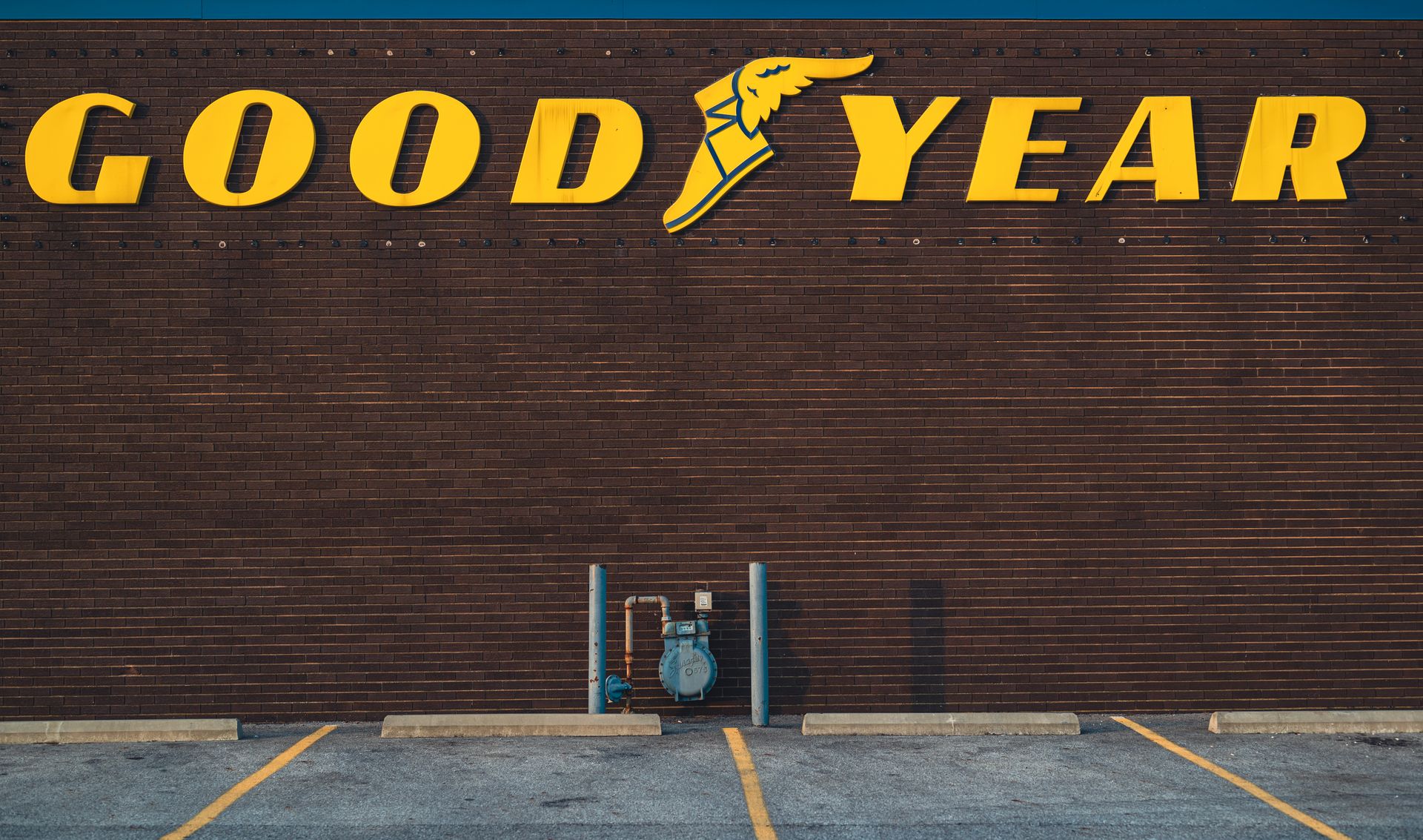 Yellow Good Year Signage on Brown Brick Wall