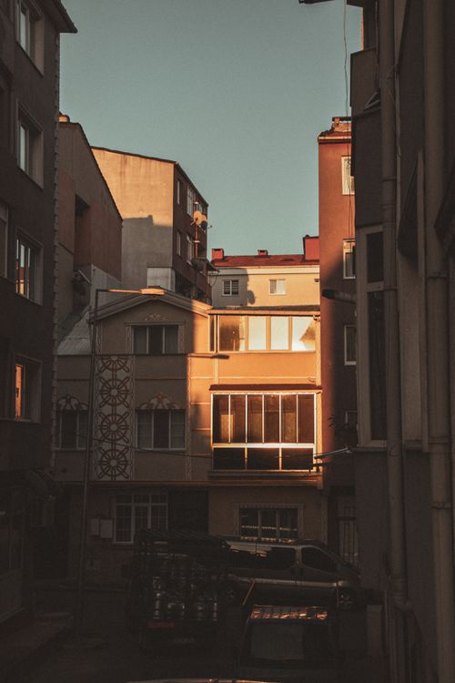 Free A cityscape featuring buildings with sunlit facades, creating dramatic shadows at sunset. Stock Photo