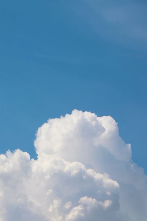 Free Vibrant cumulus cloud floating across a clear blue sky, perfect for serene scenes. Stock Photo