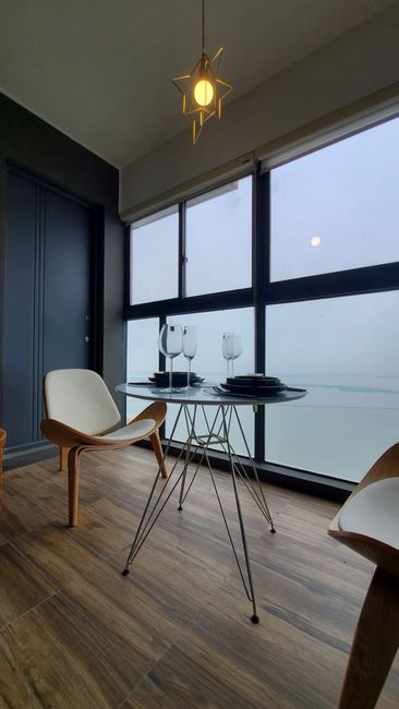 Fotomural Configuración contemporánea de comedor con sillas, mesa y vista al océano desde una ventana.