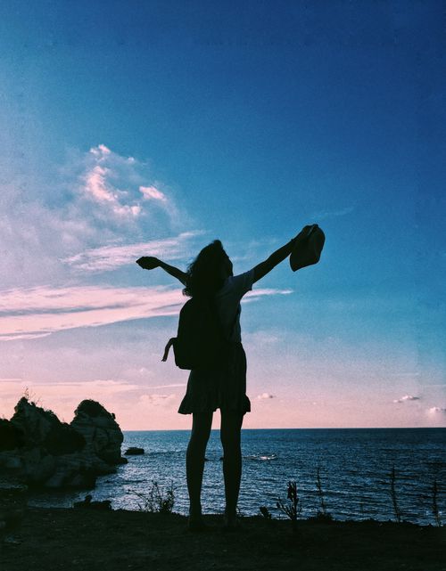 Free Silhouette of a woman with arms raised against a vibrant beach sunset in Kandıra, Turkey. Stock Photo
