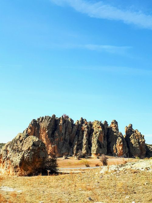 Free Jagged rock formation in a barren landscape under bright blue sky, perfect for nature themes. Stock Photo