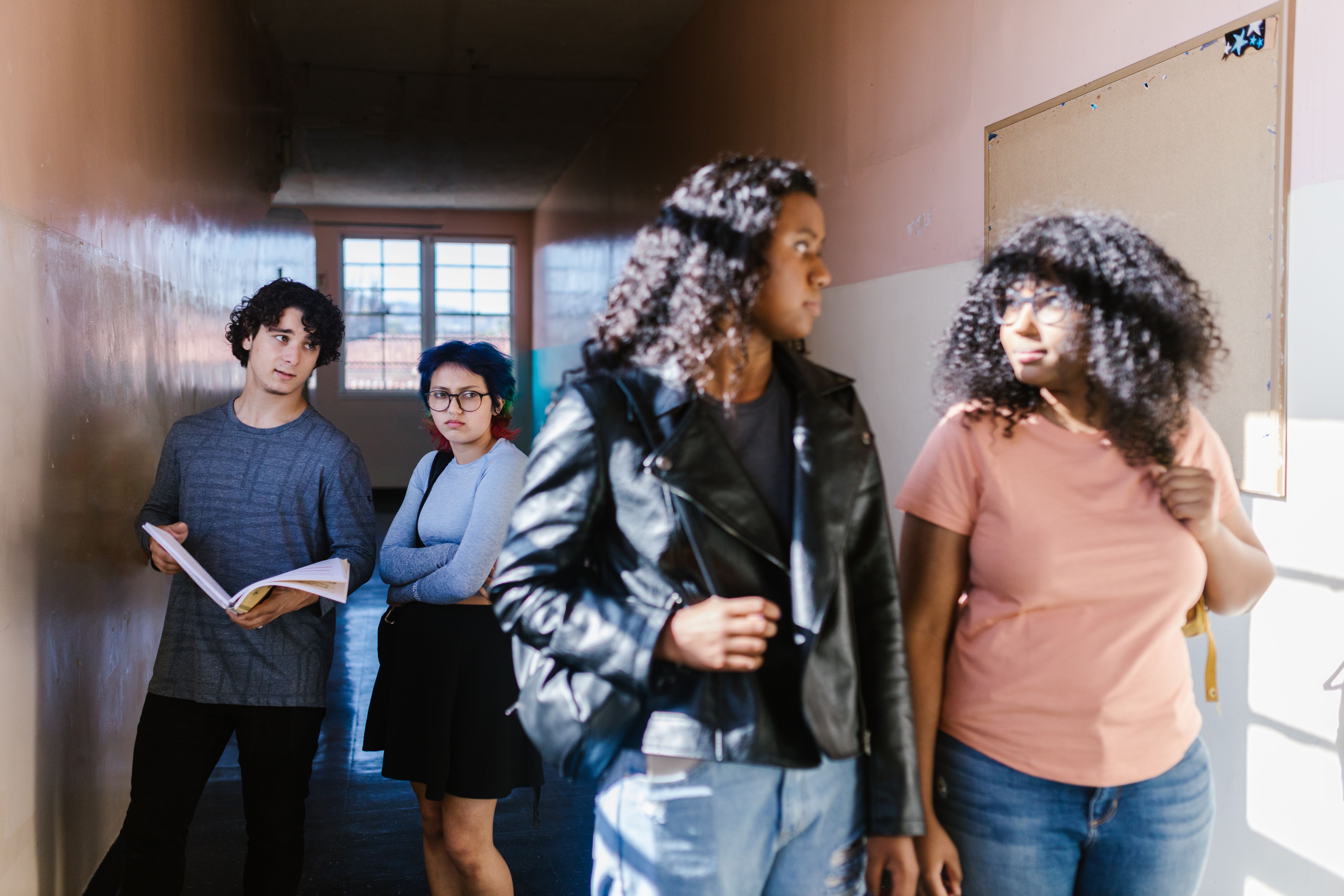 Teenagers interacting in a school corridor, conveying social dynamics and expressions.