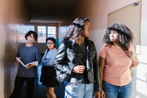 Free Teenagers interacting in a school corridor, conveying social dynamics and expressions. Stock Photo