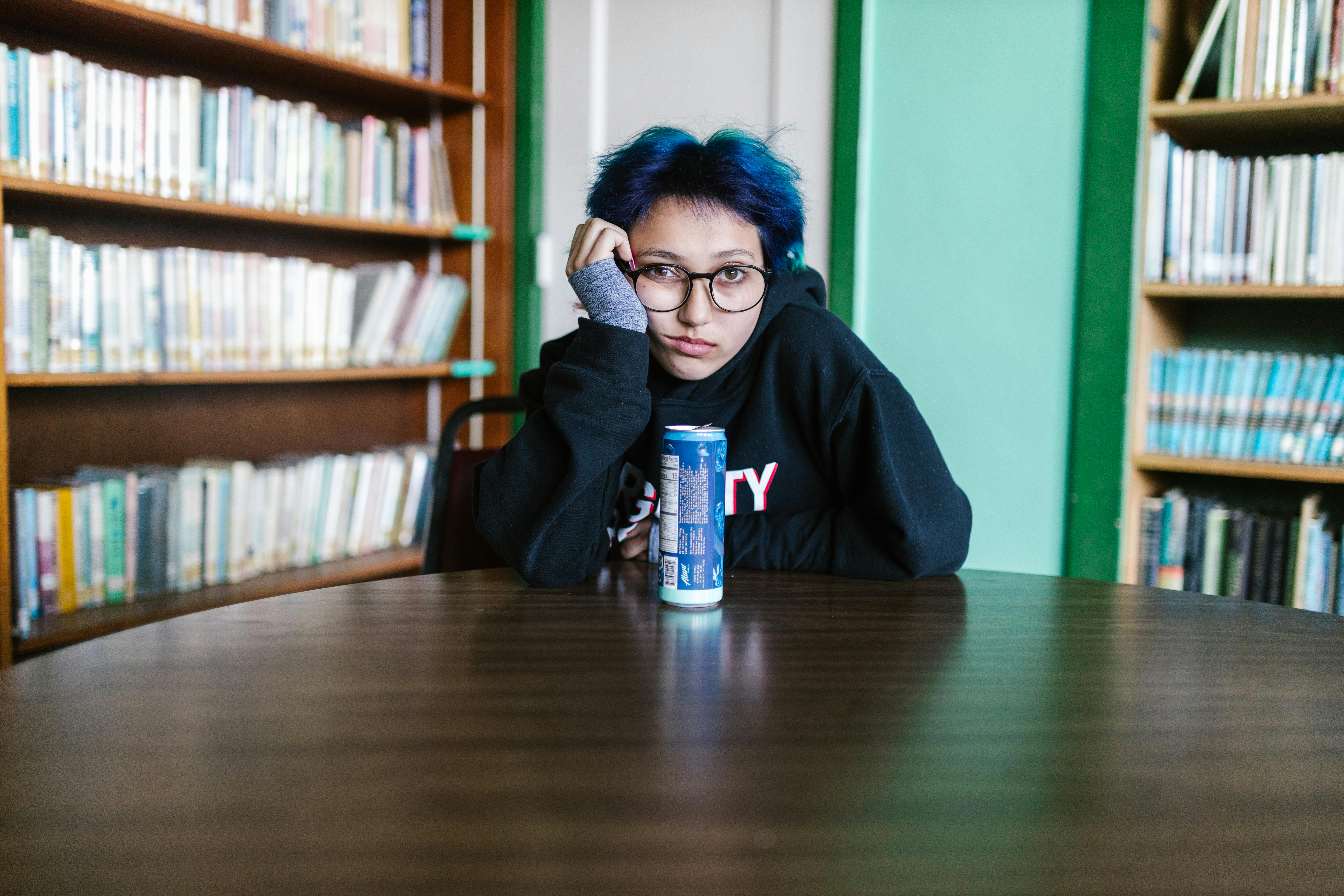 woman in black hoodie holding blue can