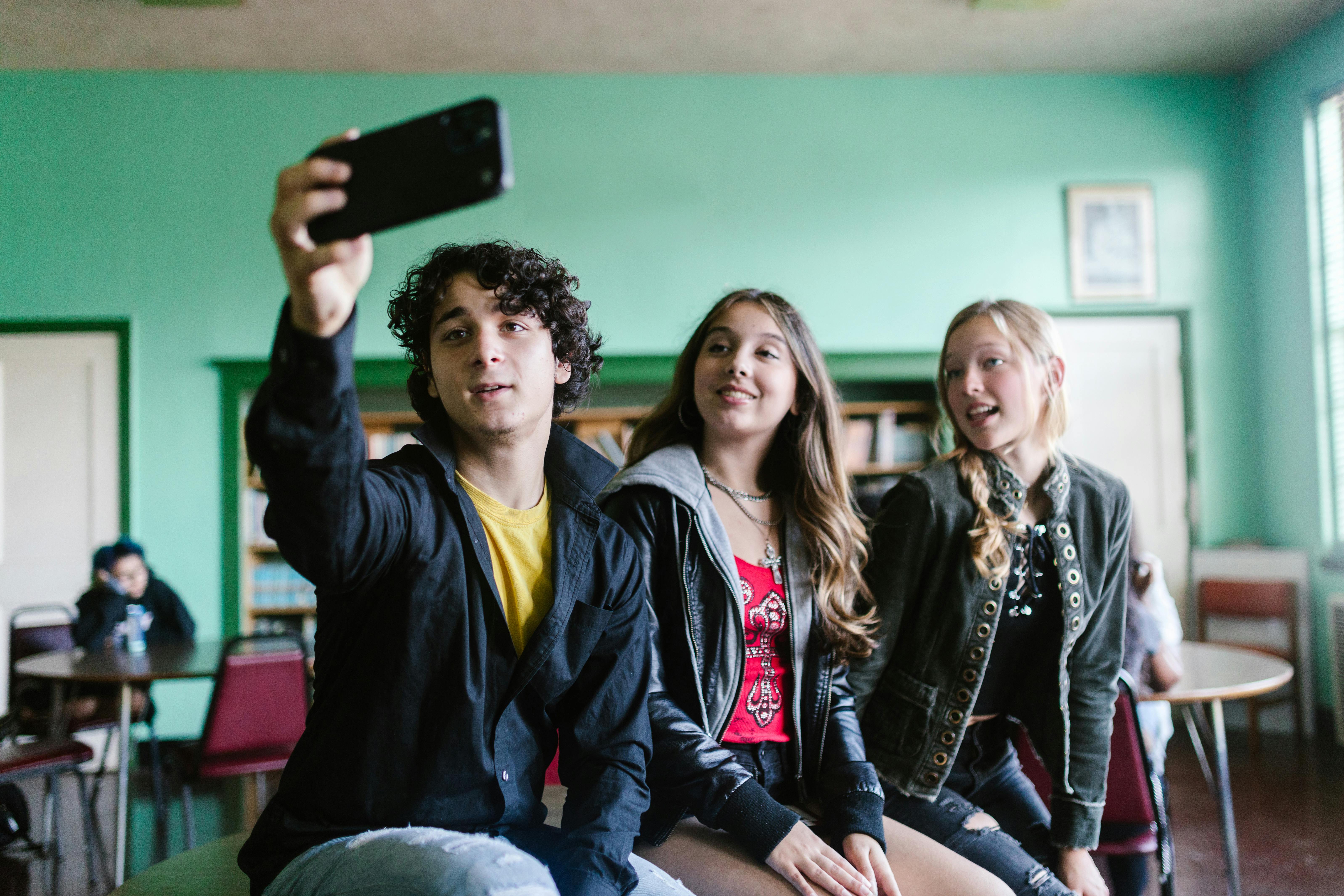 three people taking photo of themselves using a smartphone