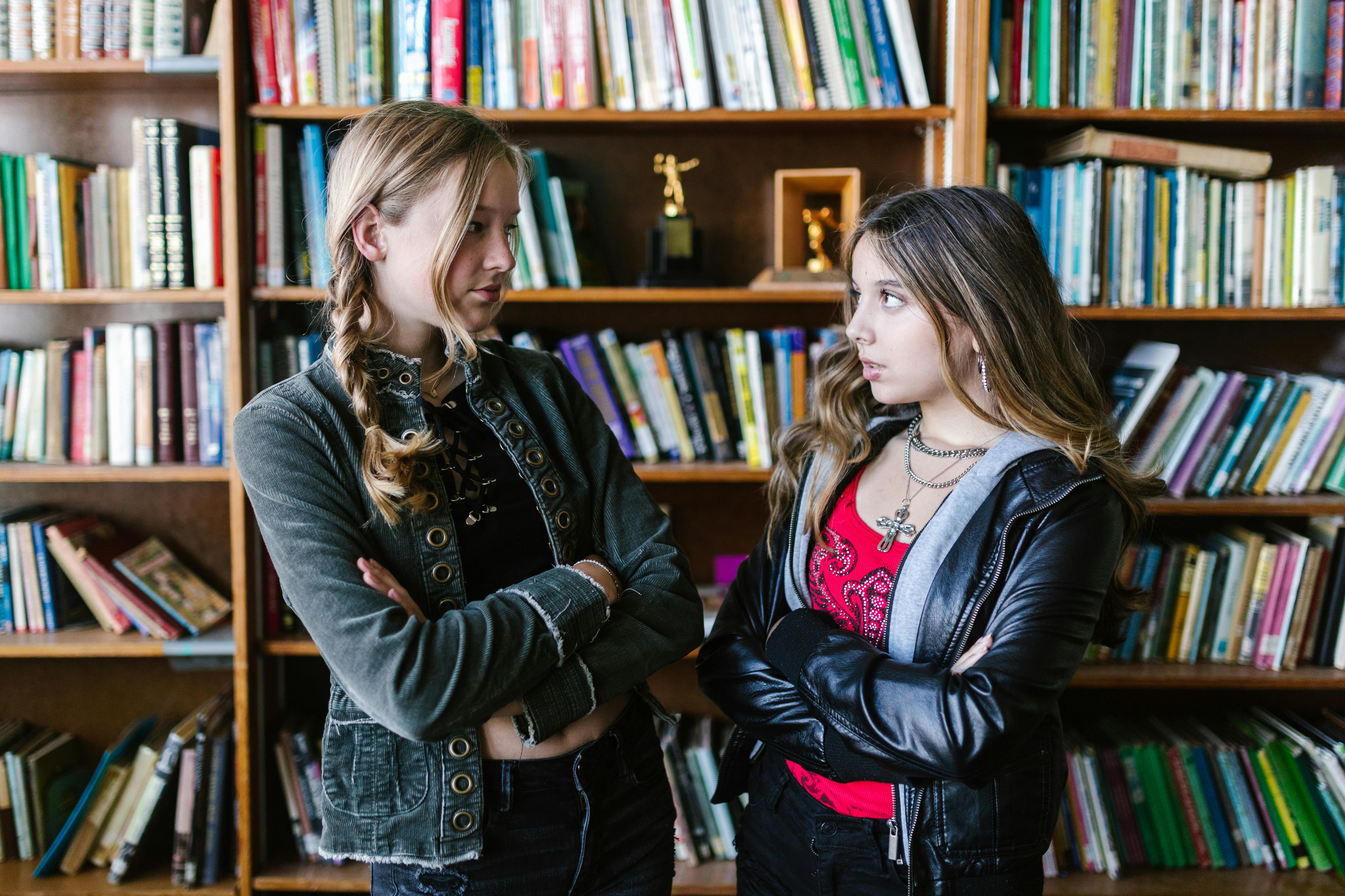 teenage girls standing near book shelves