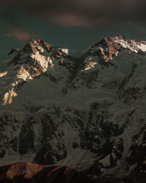 Free Stunning view of a snowcapped mountain under a dramatic sunset sky, perfect for nature lovers. Stock Photo