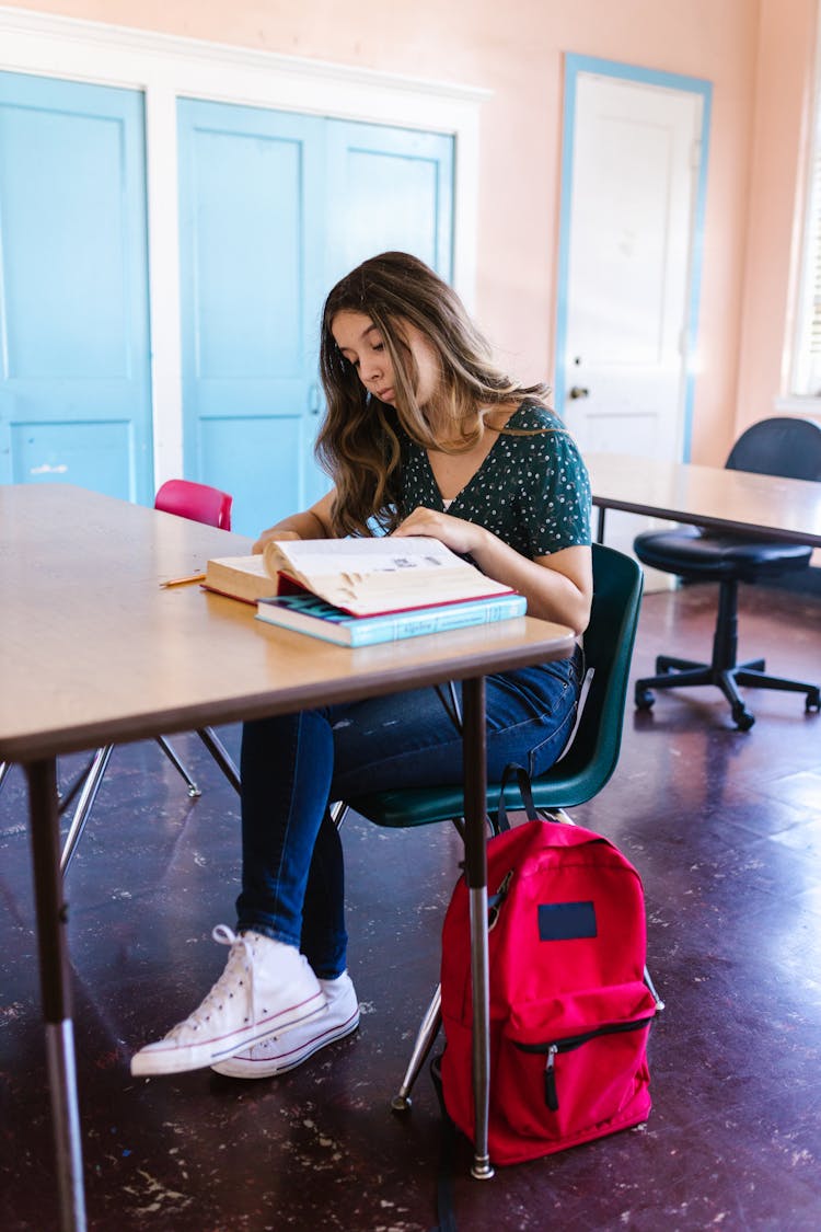 Woman Reading Book Inside A Classroom