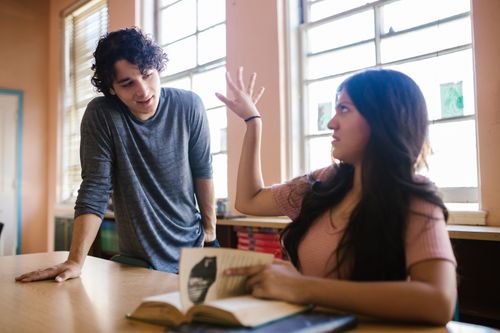 Free Two students engaged in a lively discussion in a sunlit classroom. Stock Photo
