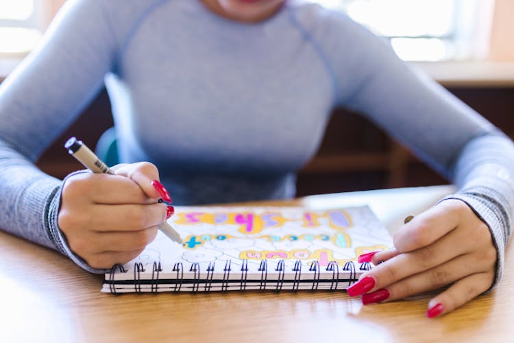 A Girl Drawing In The Notebook