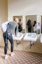 Woman in Blue Denim Jacket and Blue Denim Jeans Standing in Front of Mirror