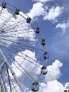 From below of Ferris wheel amusement ride for observe from height against clouds on blue sky