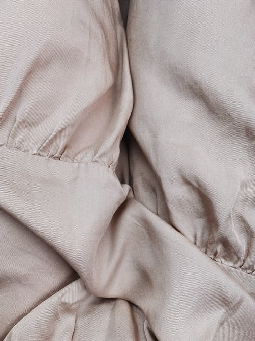 Crumpled beige cloth with wrinkles on stitches