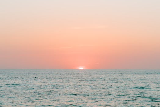 A serene sunset over the ocean with pastel skies and gentle waves, perfect for relaxation themes.