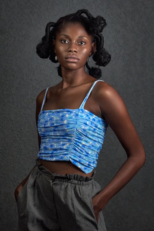 Free Elegant portrait of a young woman posing in a stylish blue top against a gray background. Stock Photo