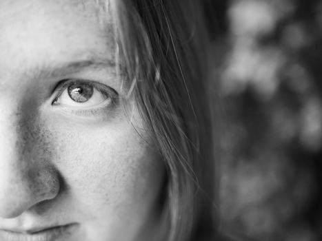 A detailed grayscale close-up of a woman's face, highlighting the eye.