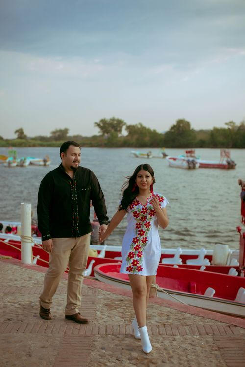 Free A happy couple walks hand in hand by a serene lakeside, capturing a moment of love and joy. Stock Photo