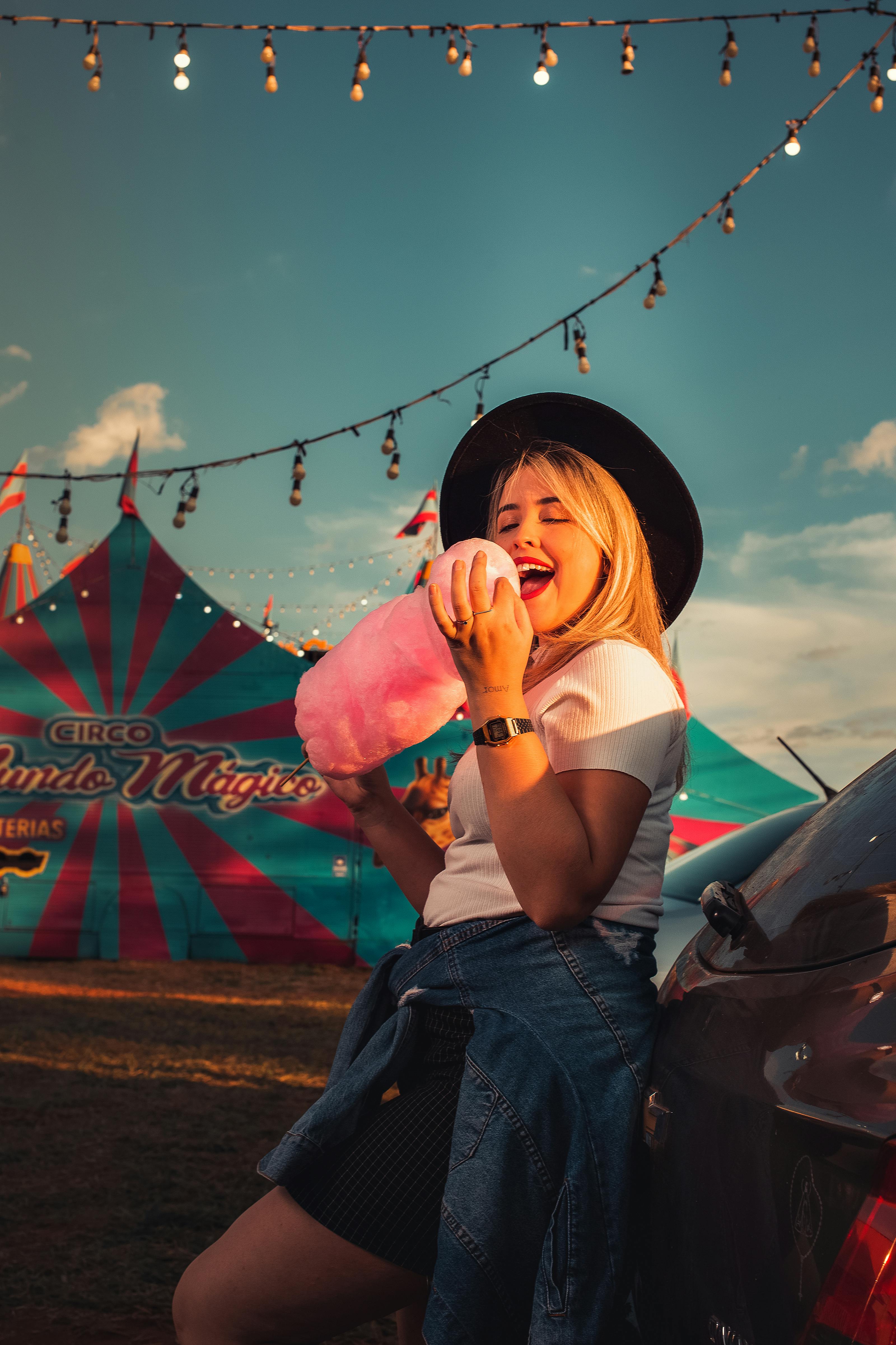 Happy Woman Eating Cotton Candy at a Festival · Free Stock Photo