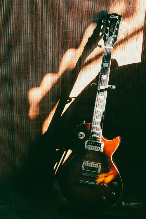 Free Electric guitar with intricate shadows against a bamboo backdrop. Stock Photo