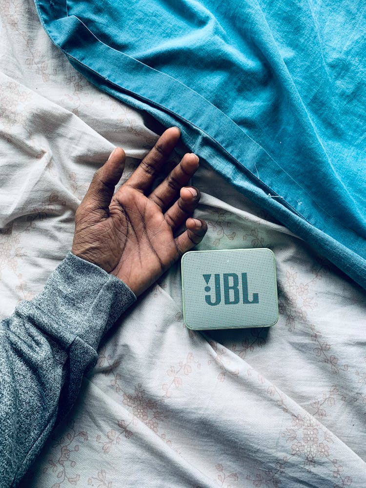 A Person's Hand And A JBL Speaker