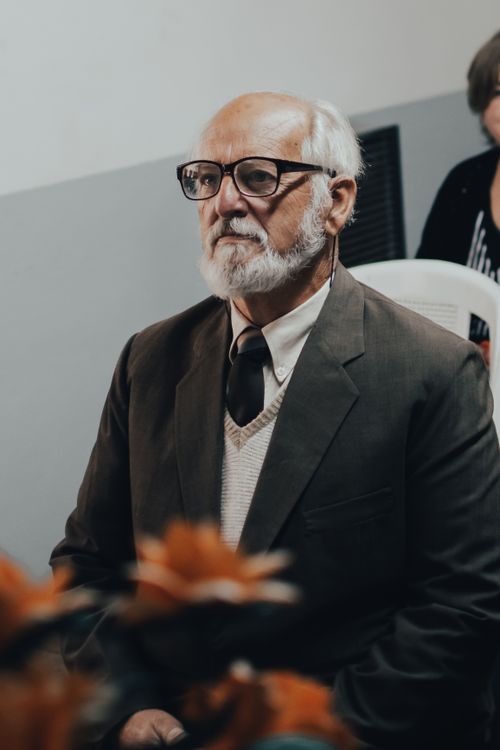 Free Elderly man with eyeglasses in formal attire looks thoughtful at an indoor event. Stock Photo