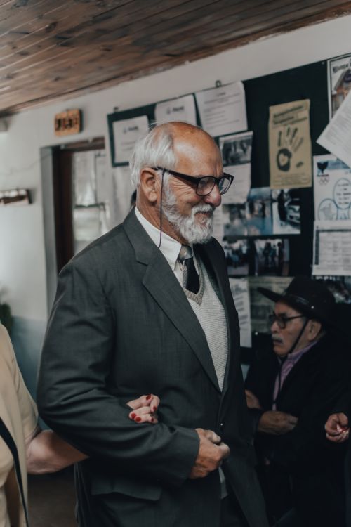 Free Senior man with beard and glasses smiling warmly indoors in formal wear. Stock Photo