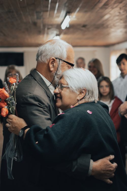 Free An elderly couple shares a heartfelt embrace during an indoor gathering with family. Stock Photo
