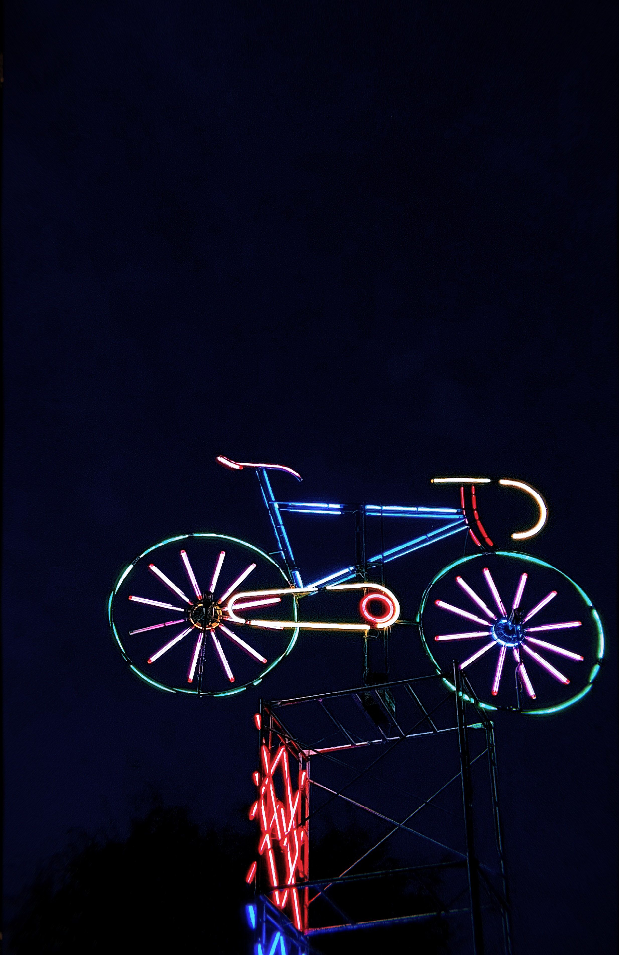 Bright neon bicycle sign glowing vibrantly against a dark night sky, creating a striking visual display.