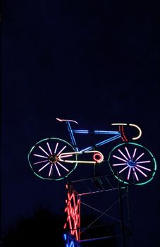 Bright neon bicycle sign glowing vibrantly against a dark night sky, creating a striking visual display.