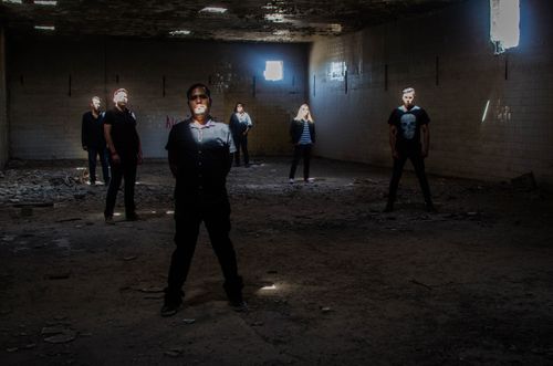 Free A group of people standing in an abandoned building, illuminated by sunlight through openings. Stock Photo