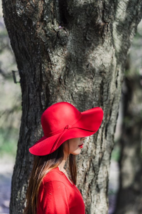 Free Woman in Red Sun Hat Standing beside the Tree Stock Photo