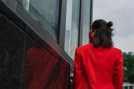 Close-Up Shot of a Woman in Red Blazer near a Wall