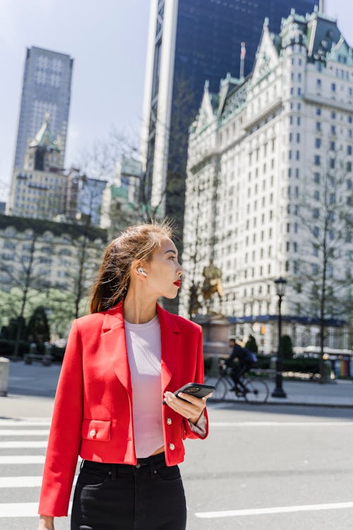 Free Woman Holding Cellphone While Looking Sideways Stock Photo