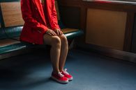 Woman in Red Blazer Sitting on Green Leather Bench