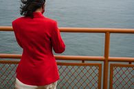 Back View of a Woman in Red Blazer near Metal Fence