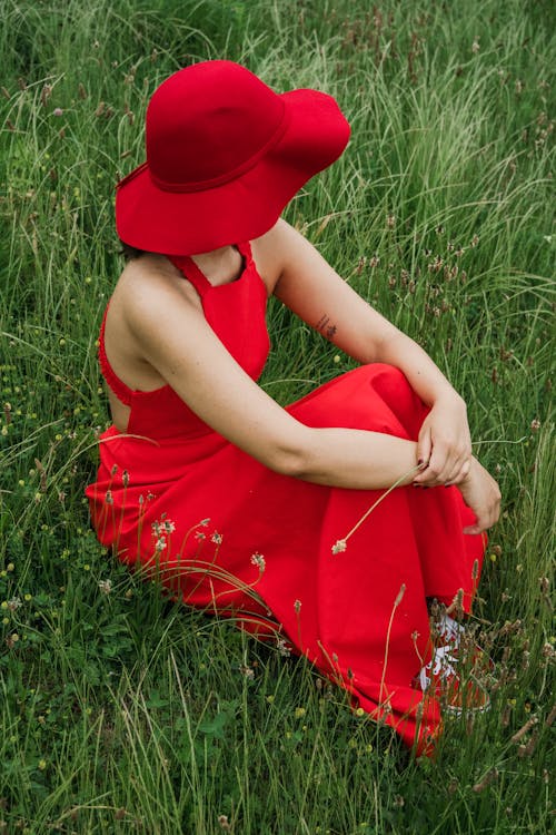 Free Woman in Red Dress Sitting on the Grass Stock Photo