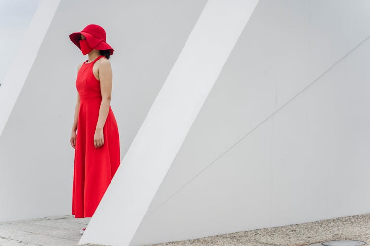 A Woman In A Red Dress Standing Still