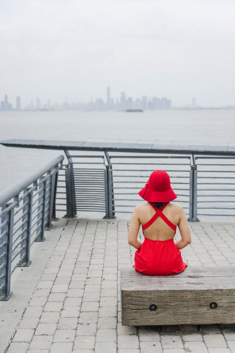 Woman In All Red Outfit Sitting On A Pier 