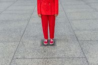 Woman in Red Coat and Pants Standing on Gray Concrete Floor