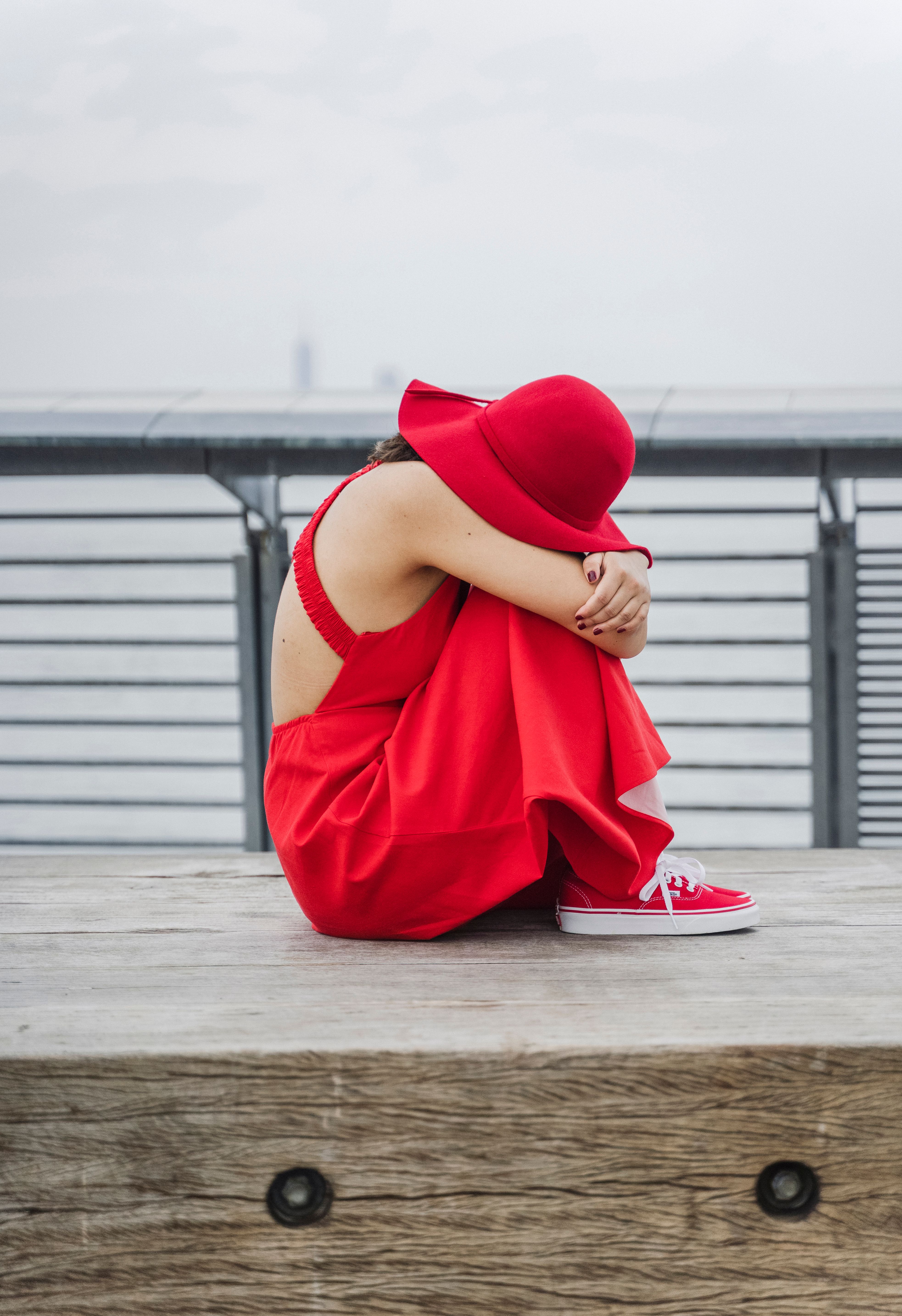 Woman in a Red Dress and Hat Sitting on the Bridge · Free Stock Photo