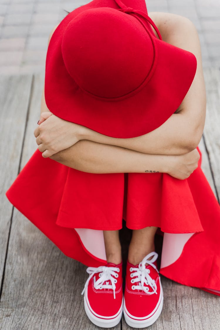 Woman In All Red Outfit Siting Hugging Her Knees