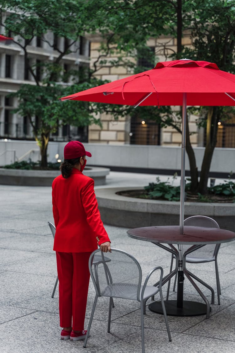 Woman Wearing A Red Outfit Standing Next To A Table In The Patio Of A Restaurant In City 