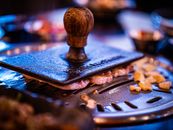 Close-up of a Korean BBQ grill with meat and garlic sizzling on the griddle.