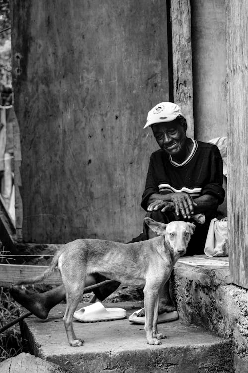 Black and White Photo of an Elderly Man Sitting Beside a Dog