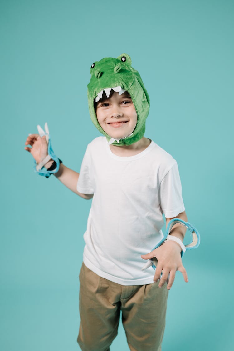 Boy In White Shirt And Brown Pants Wearing Green Animal Costume