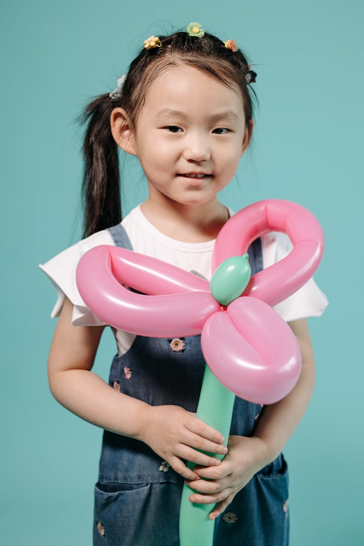 A Young Girl Smiling While Holding Balloons