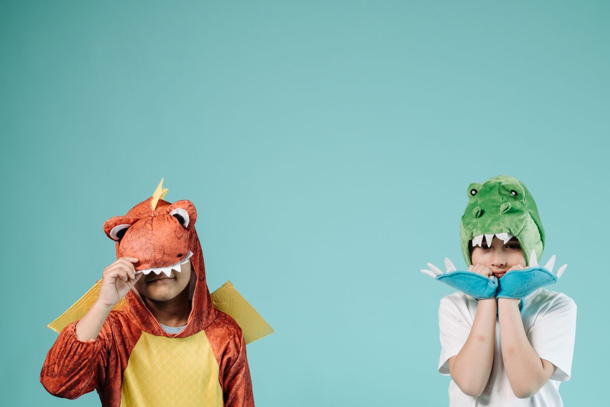 Dos niños con disfraces de dinosaurio posando de forma divertida
