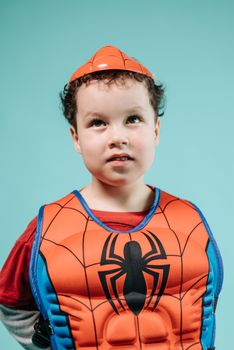 Adorable child dressed as Spiderman posing with thoughtful expression.