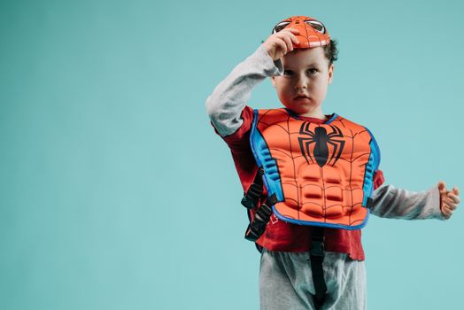 Young child wearing a Spiderman costume with a turquoise backdrop, ideal for superhero and child-themed photography.